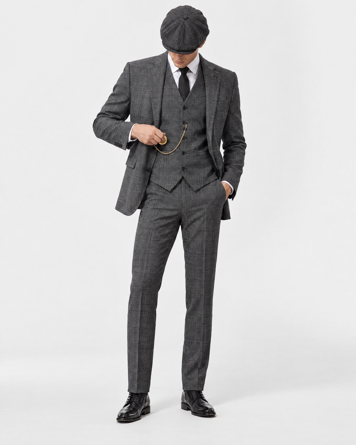 Costume gris porté en studio avec casquette et montre à gousset dorée — accessoires de mise en scène